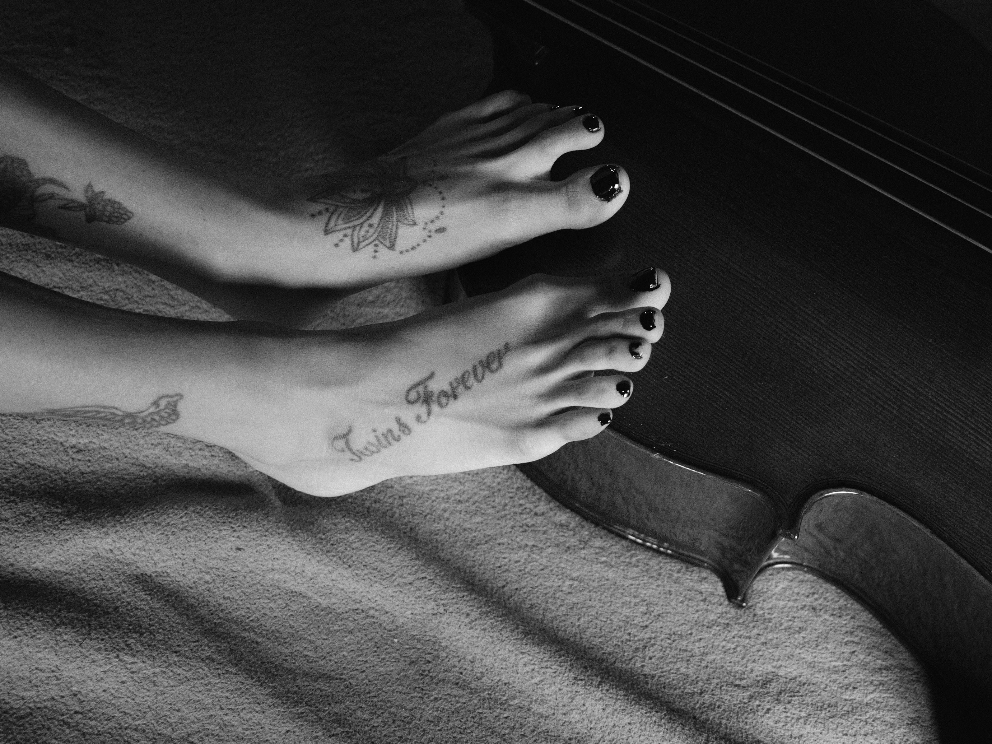 Tatuagem blackwork no pé com mandala e lettering 'Twins Forever'